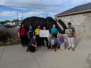 students standing with elephant sculpture made from recycled tires